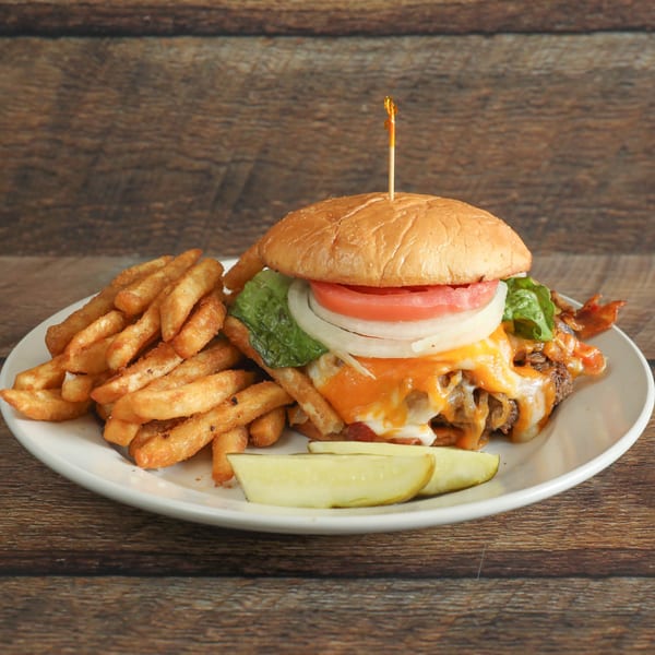 Cheeseburger with lettuce, tomato, onion, and bacon, served with fries and a pickle spear.